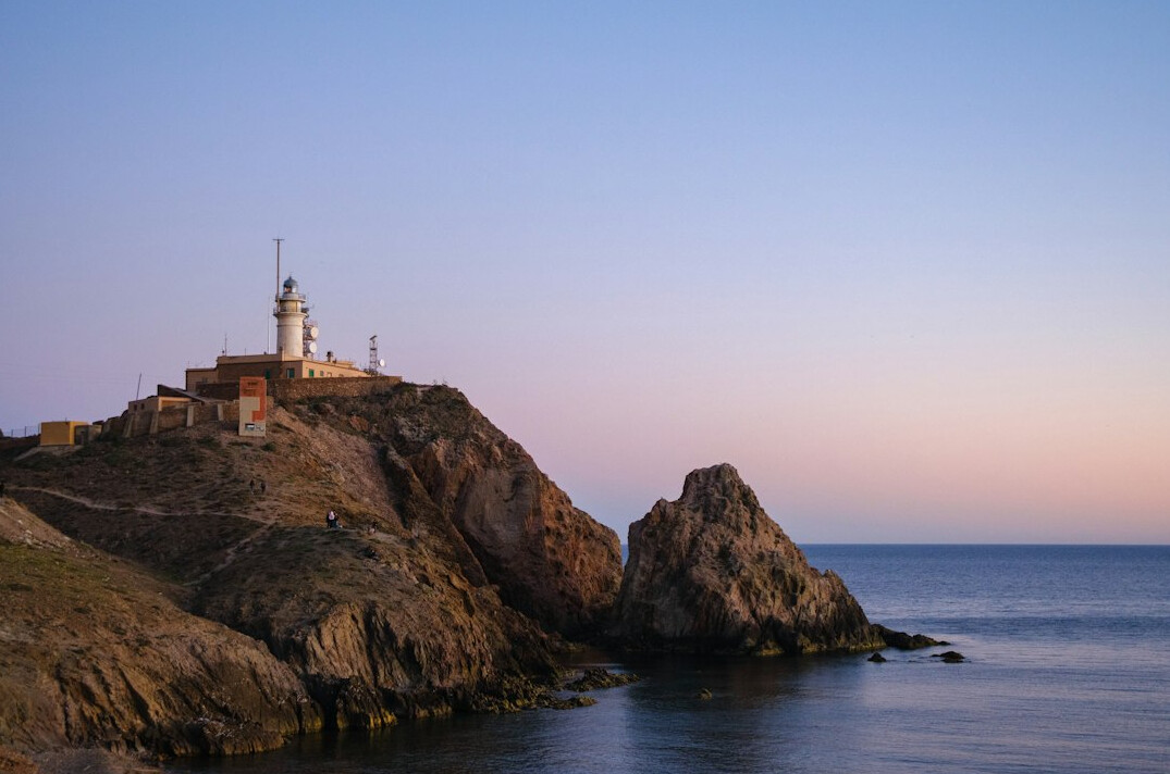 Old lighthouse on a rocky coastline at dusk