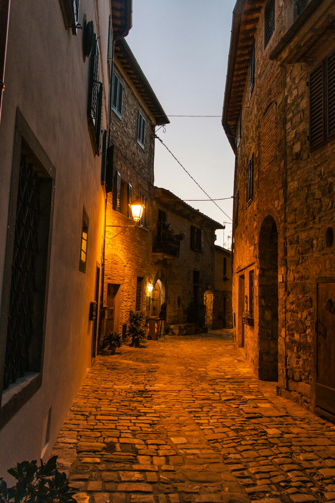 Old cobblestone street at dusk with warm lamp light
